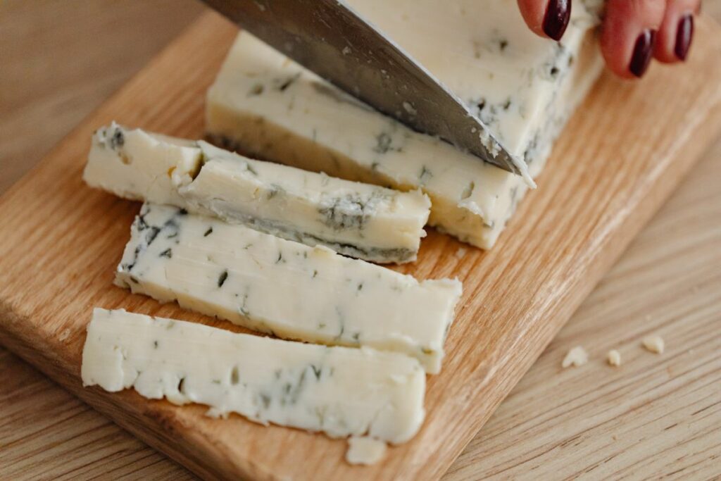 Auf einem Brett wird Gorgonzola geschnitten. Dieser Käse ist giftig für Hunde. 