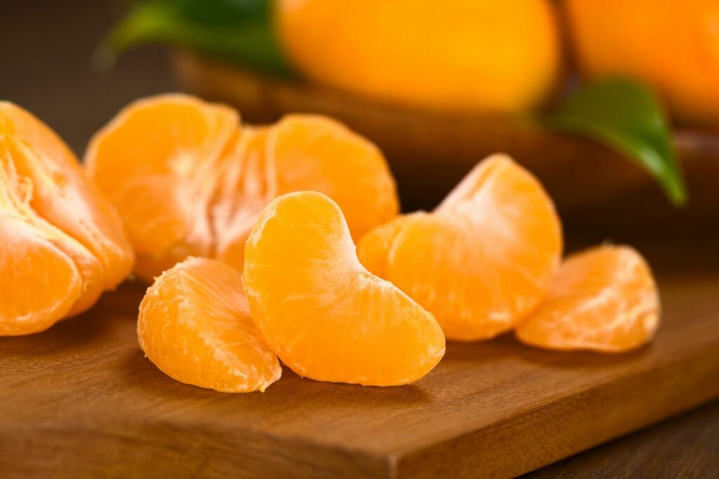 Geschälte Mandarinenstücke liegen auf einem Brett.